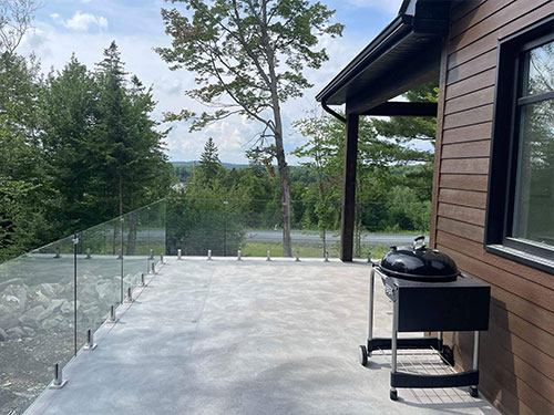 Une rampe en verre sur une terrasse surplombant les bois environnants.