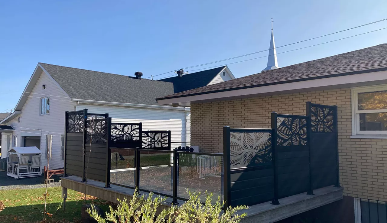 Une terrasse avec une clôture en verre et avec des murs d'intimité, offrant un espace extérieur abrité et confortable.