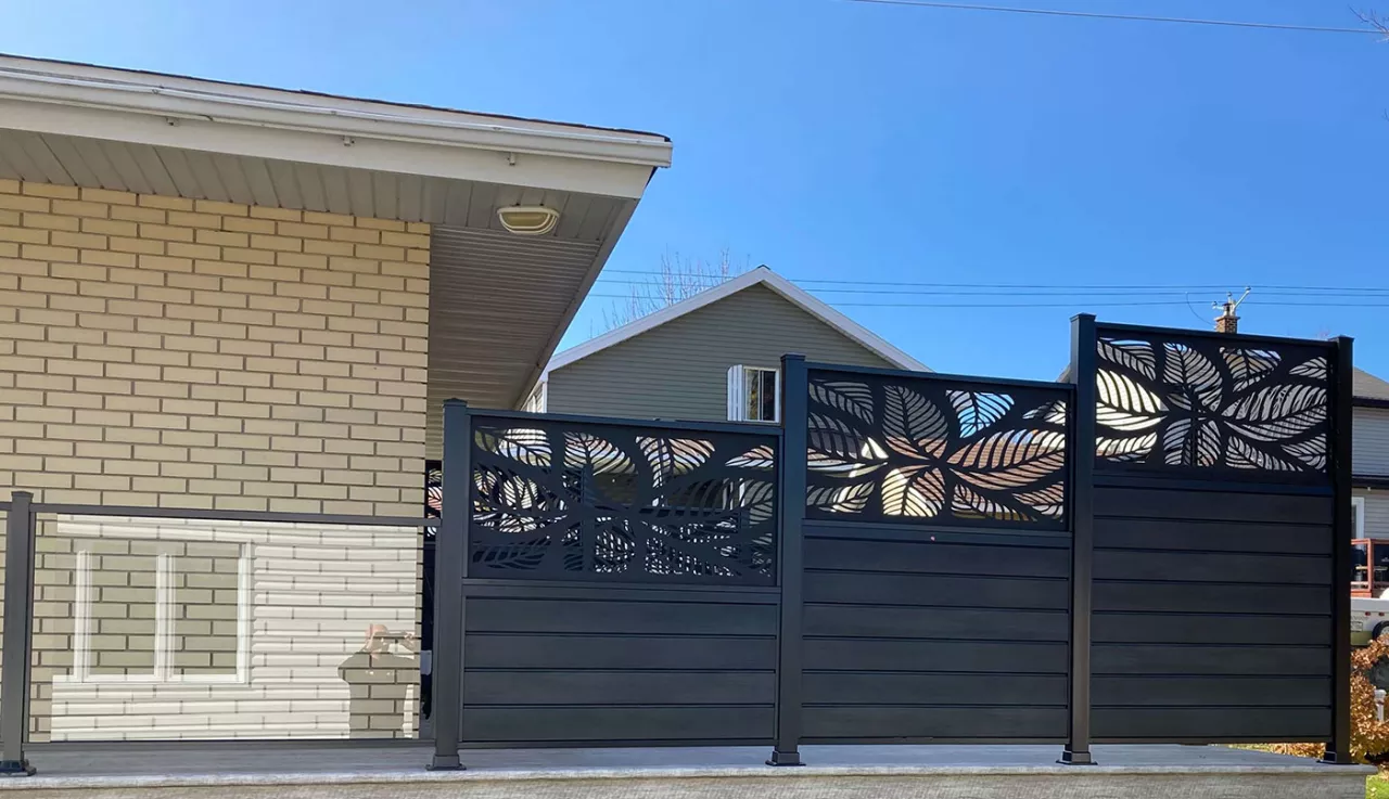 Une clôture noire ornée de motifs décoratifs, avec clôture en verre, ajoutant une touche d'élégance à l'environnement.